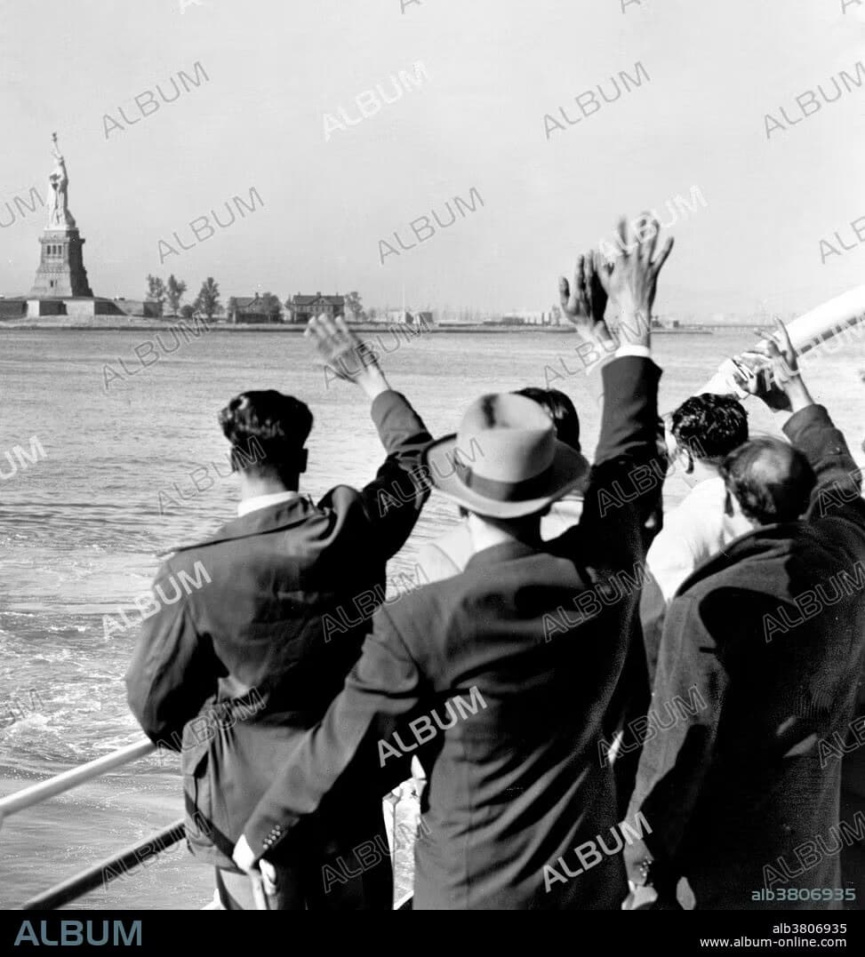 New arrivals waving to the Statue of Liberty from a boat in New York Harbor