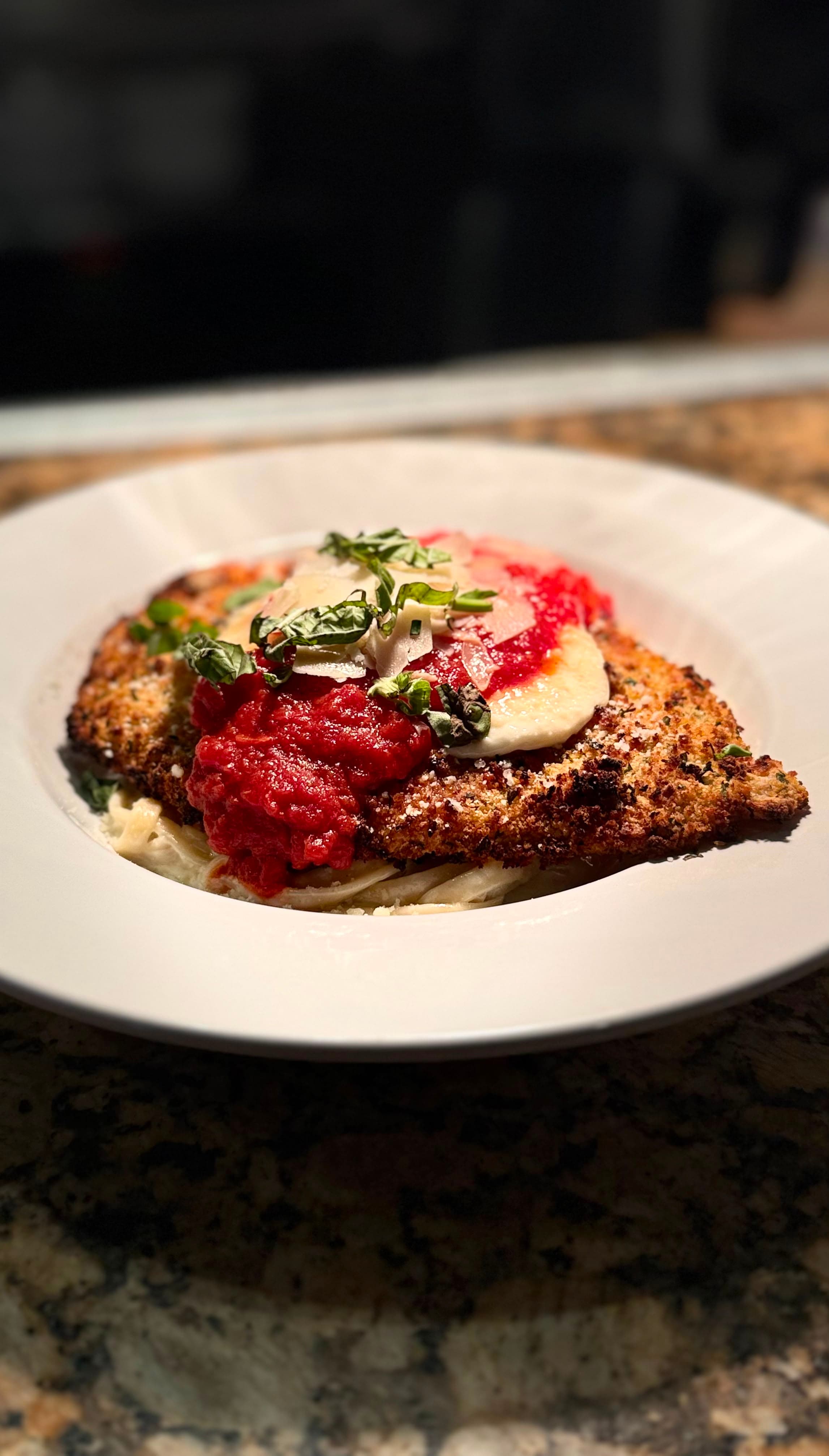 Chicken Parmesan — herb-crusted chicken with mozzarella over fettuccine Alfredo