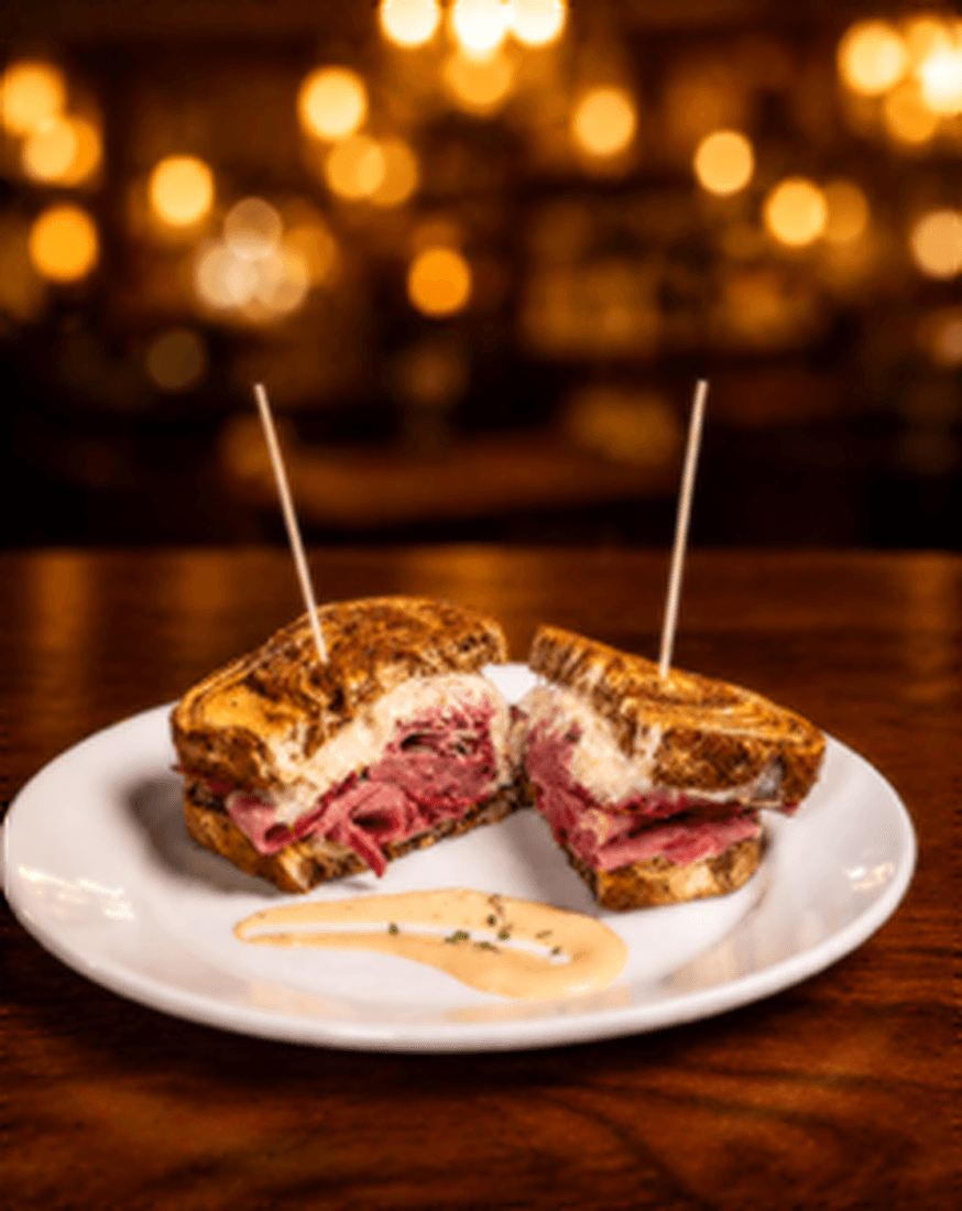 Toasted pressed Cuban sandwich cut in half with a side of dipping sauce